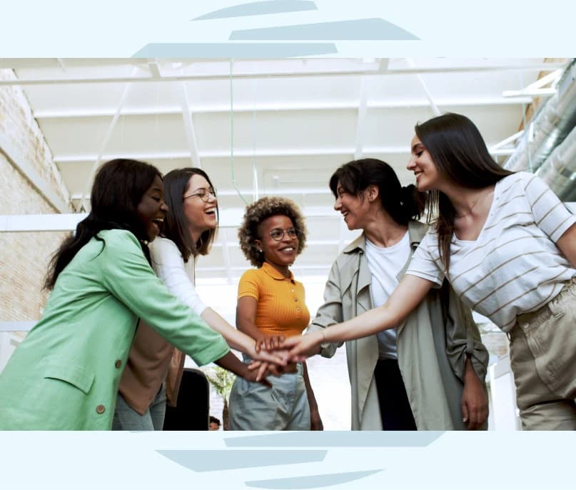 Fünf Frauen reichen sich die Hände und symbolisieren damit Einigkeit und Selbstbestimmung in den Workshops zu Frauen und Finanzen.